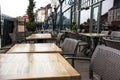 Wooden tables with metal chairs outside a cafe on a high street. No people seated