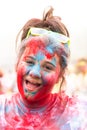 Teenage girl smiles for the camera after finishing a Colour Paint Run. She is covered in blue and red paint with yellow sunglasse