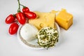 Types of cheese and tomato heap on plate on white table