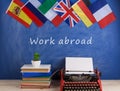 typewriter, flags of Spain, France, Great Britain, books and other countries and blackboard with text & x22;Work abroad