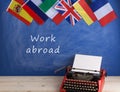 typewriter, flags of Spain, France, Great Britain and other countries and blackboard with text & x22;Work abroad Royalty Free Stock Photo