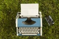 Typewriter and old camera on Grass background
