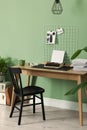 Typewriter, stack of papers and mood board on wooden table near pale green wall. Writer`s workplace