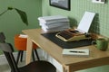 Typewriter, stack of papers and mood board on wooden table near pale green wall. Writer`s workplace