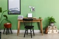 Typewriter, stack of papers and mood board on wooden table near pale green wall. Writer`s workplace