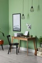 Typewriter, stack of papers and mood board on wooden table near pale green wall. Writer`s workplace