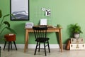 Typewriter, stack of papers and mood board on wooden table near pale green wall. Writer`s workplace