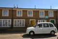 Typical ancient flat building in Bethnal Green East London and a white iconic taxi cab car