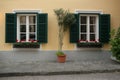 A typical austrian window with green louvered shuters and square paned windows with flowers in hanging flower pots