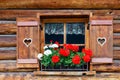 Typical bavarian or austrian wooden window with red geranium flowers on house in Austria or Germany