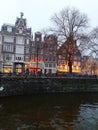 Typical brick tourist buildings and shops along the water of the canals of the river in amsterdam