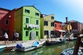Typical brightly colored houses and narrow channels with tourists in Burano, Venice, Italy.