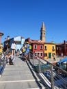 Typical brightly colored houses and narrow channels with tourists in Burano, Venice, Italy