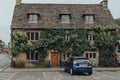 A typical Cotswolds cottage home in Bourton-on-the-Water, Cotswolds, UK. Covered in ivy, car parked at the front