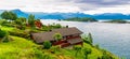 Typical countryside Norwegian landscape with red painted houses on the shore of the fjord. Cloudy summer morning in Norway, Europe