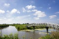 Typical Dutch landscape with green meadows, grass, bridge, water, blue sky and clouds Royalty Free Stock Photo