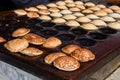 Typical Dutch poffertjes - tiny pancakes-being baked on a heavy cast iron pan Royalty Free Stock Photo