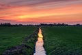 Typical Dutch polder landscape with reflection of a multi coloured sunset sky on the water in a ditch Royalty Free Stock Photo