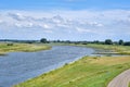 Typical Dutch river landscape with cows, grassland, floodplain and the river Rhine with groyne in river bend near