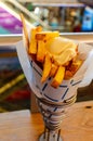 Typical Dutch street food .Hand holding traditional potato dish from Netherlands. Fried potatoes in paper cone topped with