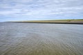 Typical dutch view of a dike, seawall, with sheeps green grassland and the Wadden sea. Sedyk, Friesland, Harlingen, The Royalty Free Stock Photo