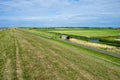 Typical dutch view of a dike with sheeps overlooking the polder with farms, green grassland and the Wadden sea. Sedyk