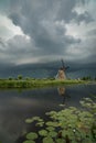 Typical dutch windmill with a thunderstorm approaching in the background. Dramatic sky over the wide open landscape of Holland Royalty Free Stock Photo