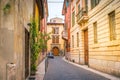 European small narrow cobblestone street with old bright houses, windows with shutters in Verona, Italy