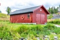 Typical Fishermen`s Boathouse In Norway - Classical Red, Wooden Scandinavian Small Building. Green Grass, Close To Coast. The