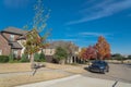 Typical front porch entrance of new suburban houses with parked car on colorful fall street outside Dallas, Texas, USA