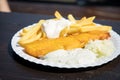 Typical German Friesland deep fried Pollack fish in beer batter with French fries, mayonnaise, sauce tartar and coleslaw on wooden Royalty Free Stock Photo