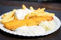 Typical German Friesland deep fried Pollack fish in beer batter with French fries, mayonnaise, sauce tartar and coleslaw on wooden Royalty Free Stock Photo