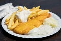 Typical German Friesland deep fried Pollack fish in beer batter with French fries, mayonnaise, sauce tartar and coleslaw on wooden Royalty Free Stock Photo