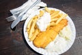 Typical German Friesland deep fried Pollack fish in beer batter with French fries, mayonnaise, sauce tartar and coleslaw on wooden Royalty Free Stock Photo