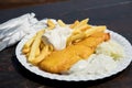 Typical German Friesland deep fried Pollack fish in beer batter with French fries, mayonnaise, sauce tartar and coleslaw on wooden Royalty Free Stock Photo