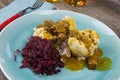 Typical german hearty meal: closeup of dumplings with brown sauce, red cabbage, goulash meat on blue china dish