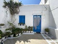 Typical greek front yard with white wall, blue door and lots of plants to decorate