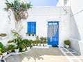 Typical greek front yard with white wall, blue door and lots of plants to decorate