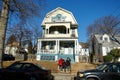 Typical house in New Jersey with parked cars next to the sidewalk on a sunny day.