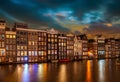 Typical houses on the Damrak at night, in Amsterdam, the Netherlands