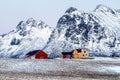 Lofoten islands, Norway. Typical houses of the fishermen rorbu, on the snowy beach, mountains in background. Royalty Free Stock Photo