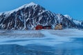 Lofoten islands, Norway. Typical houses of the fishermen rorbu, on the snowy beach, mountains in background. Royalty Free Stock Photo