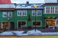 Typical Icelandic green wooden house with snow on the roof in a Reykjavik street and shops with windows with a snow covered