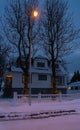 Typical icelandic white wooden house with a snowy roof in Selfoss on a cloudy evening with Christmas lights on the trees at the