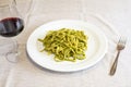 typical italian fettuccine recipe with pesto sauce on table with linen tablecloth, fork Royalty Free Stock Photo