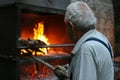 A typical Italian village. Gray-haired old man lights a fire in the oven