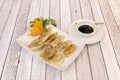 Typical Japanese meatballs cooked on the grill gyozas with a carrot flower and soy sauce in a white bowl