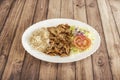 A typical kebab dish with grilled minced lamb meat on a skewer with basmati rice and lettuce, tomato and red onion salad on wooden