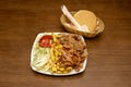 Typical kebab plate with mixed lamb meat with chicken, white onion and lettuce together with a portion of French fries on a white