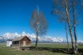 Typical landscape with a cabin and some trees in the foreground and the snowy mountains of Grand Tetons National Park in the Royalty Free Stock Photo